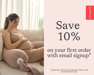 Pregnant woman sitting on a couch with a bbhugme pregnancy pillow, promotional text for 10% off with email signup.