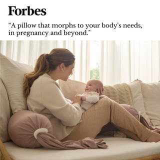 Woman holding a baby on a couch with a pillow labeled