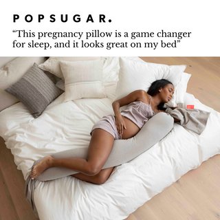 Woman lying on a bed with a pregnancy pillow