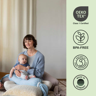 Woman holding a bbhugme nursing pillow with Oeko-Tex and BPA-free certification logos on the right.