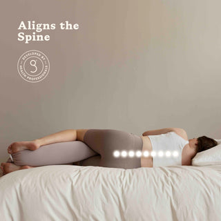 Person lying on a bed with a bbhugme pregnancy pillow under their head, promoting spinal alignment.