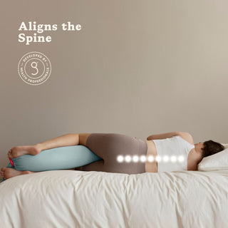 Person lying on a bed with a bbhugme pregnancy pillow, emphasizing spine alignment.