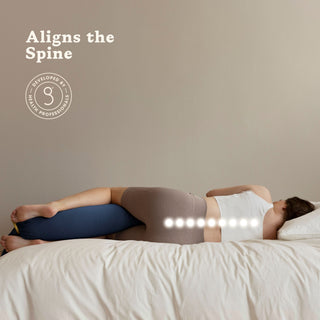 Person lying on a bed with a bbhugme pregnancy pillow under their head, aligning the spine.