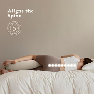 Person lying on a bed with a bbhugme pregnancy pillow under their head, promoting spinal alignment.