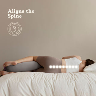 Person lying on a bed with a bbhugme pregnancy pillow under their head, promoting spinal alignment.